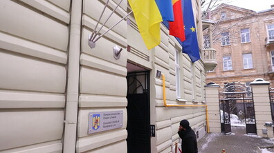 The Honorary Consulate of Romania, at the entrance to which hang three flags: Ukraine, Romania and the European Union. Below is a sign with the inscription Honorary Consulate of Romania in Lviv. A man enters the building.