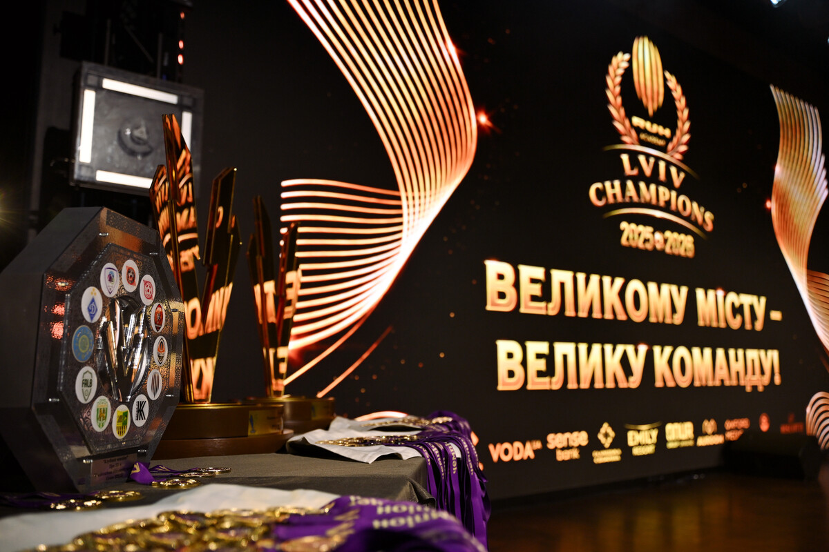 Ліворуч видніються кубки. На задньому фоні гасло події: "Великому місту - велику команду"