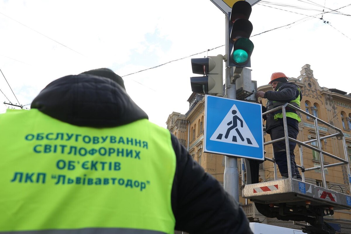 Працівник на автовишці налаштовує обладнання світлофора