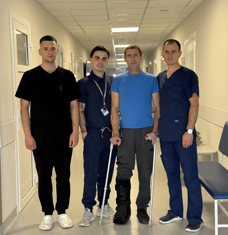 пацієнт з лікарями, які його оперували, стоять у холі лікарні