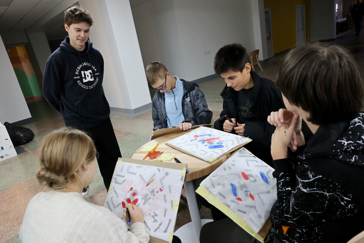 п&rsquo;ятеро підлітків сидять за столом, міркуючи над проєктом. В кожного в руках мапа з планом території та маркери