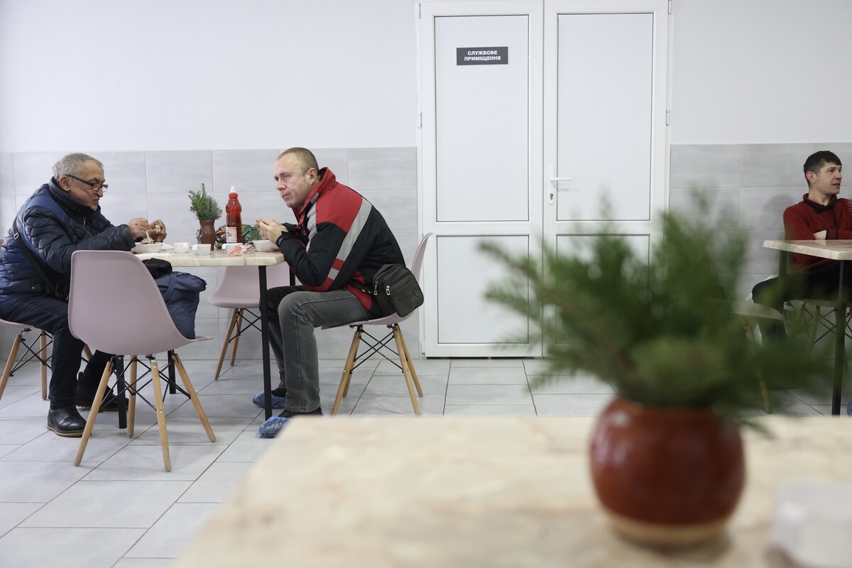 Двоє чоловіків їдять за столом у центрі допомоги бездомним