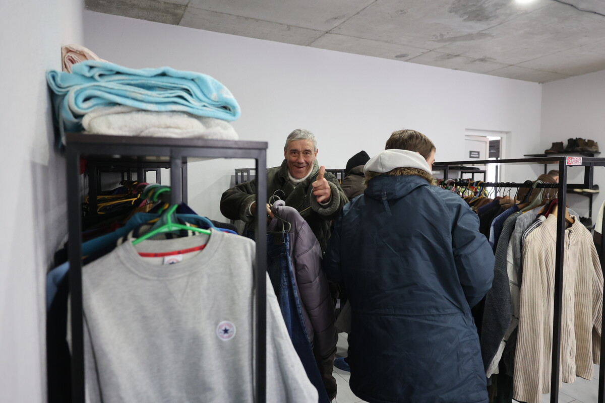 Бездомний чоловік обирає собі одяг та усміхається