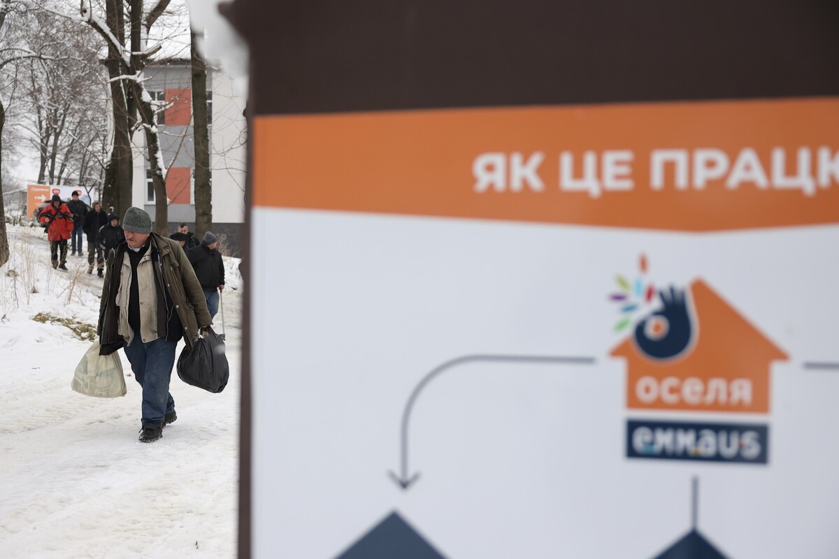 Бездомний чоловік йде до "Оселі", у обох руках тримає пакети