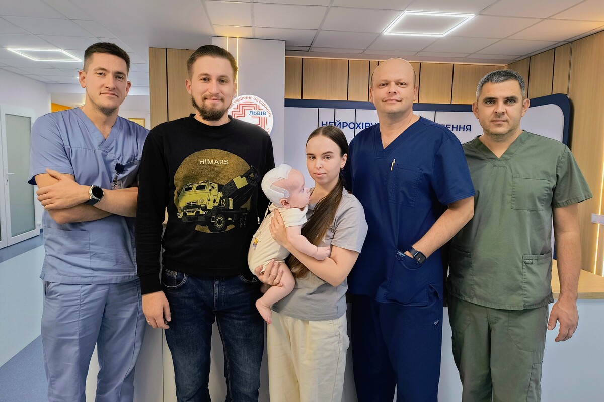 Батьки з немовлям та лікарями, які оперували малюка, стоять у лікарняному холі