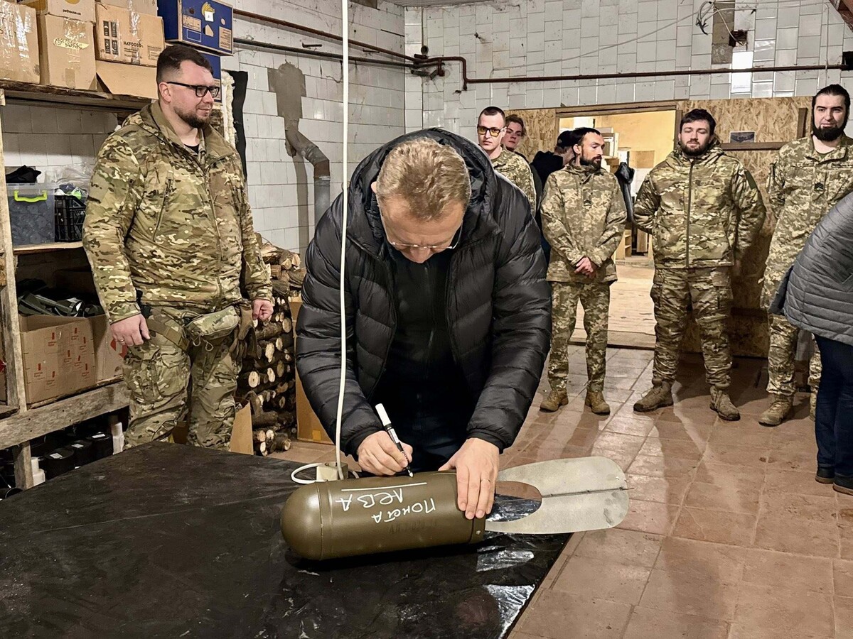 Мер підписує боєприпас. Довкола нього захисники у військовій формі