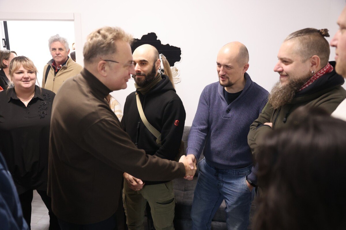 Міський голова Львова Андрій Садовий тисне руку чоловіку. В кімнаті присутні ветерани, представники міської та обласної влади та ГО "Родин полеглих захисників Львівщини"