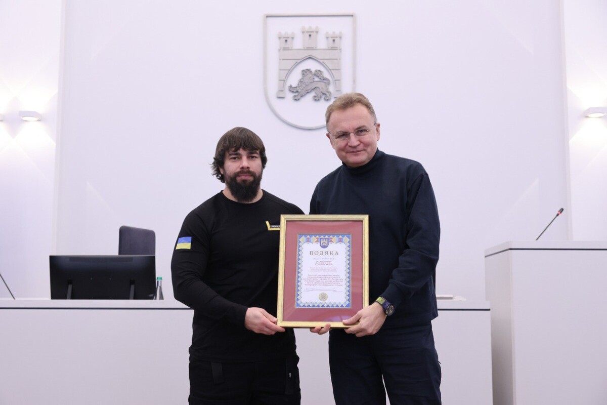 Мер Львова Андрій Садовий разом з Володимиром Рудковським. Разом тримають подяку. Позаду них - Герб Львова.