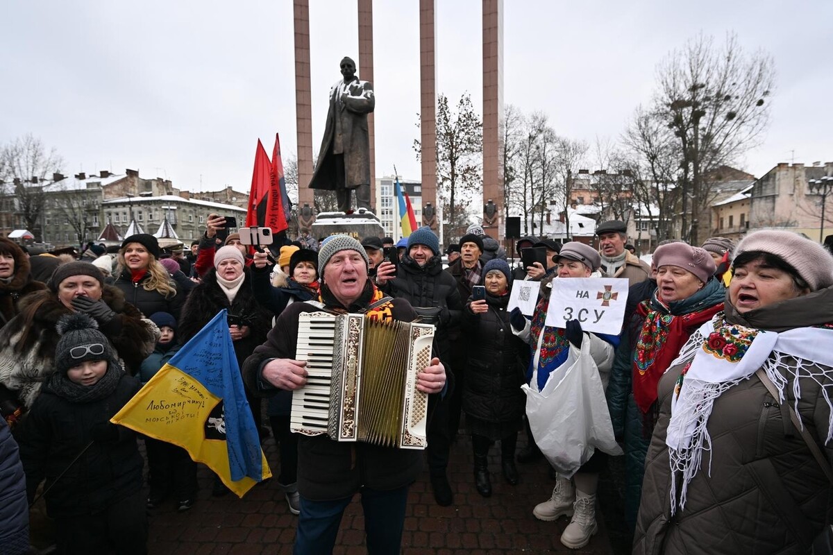 Пан Ярослав під час віча біля пам'ятника Степанові Бандері співає та грає на акордеоні. Поруч співають учасники колективу &ldquo;Західний вітер&rdquo;.