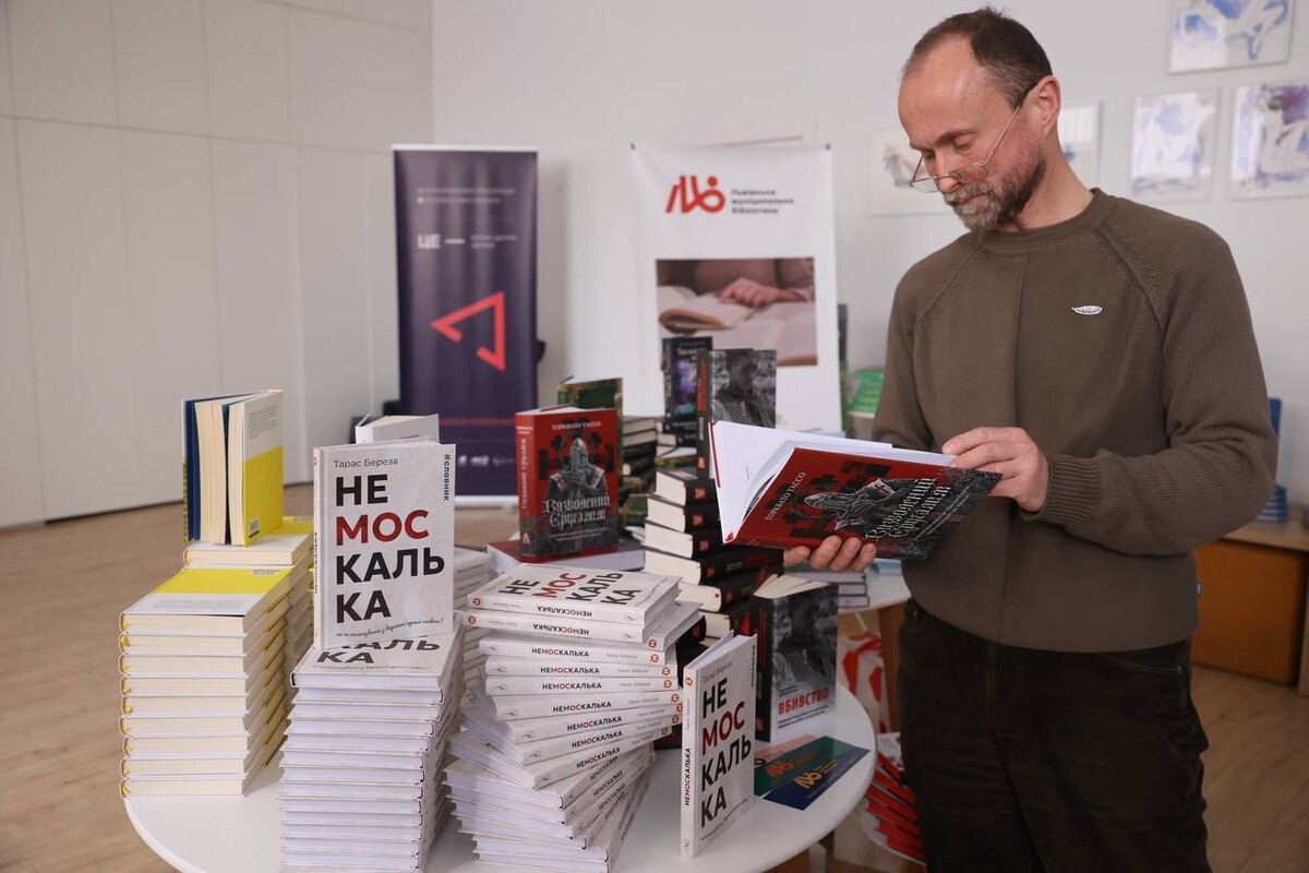Василь Кметь тримає у руках книгу. Поруч виставлені інші книги, що перемогли у конкурсі.
