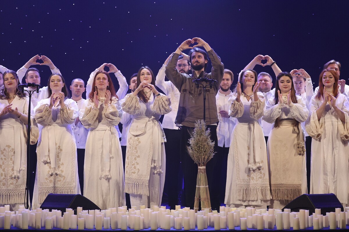 Учасники хору “Гомін” на сцені аплодують, дехто склав руки в формі серця.