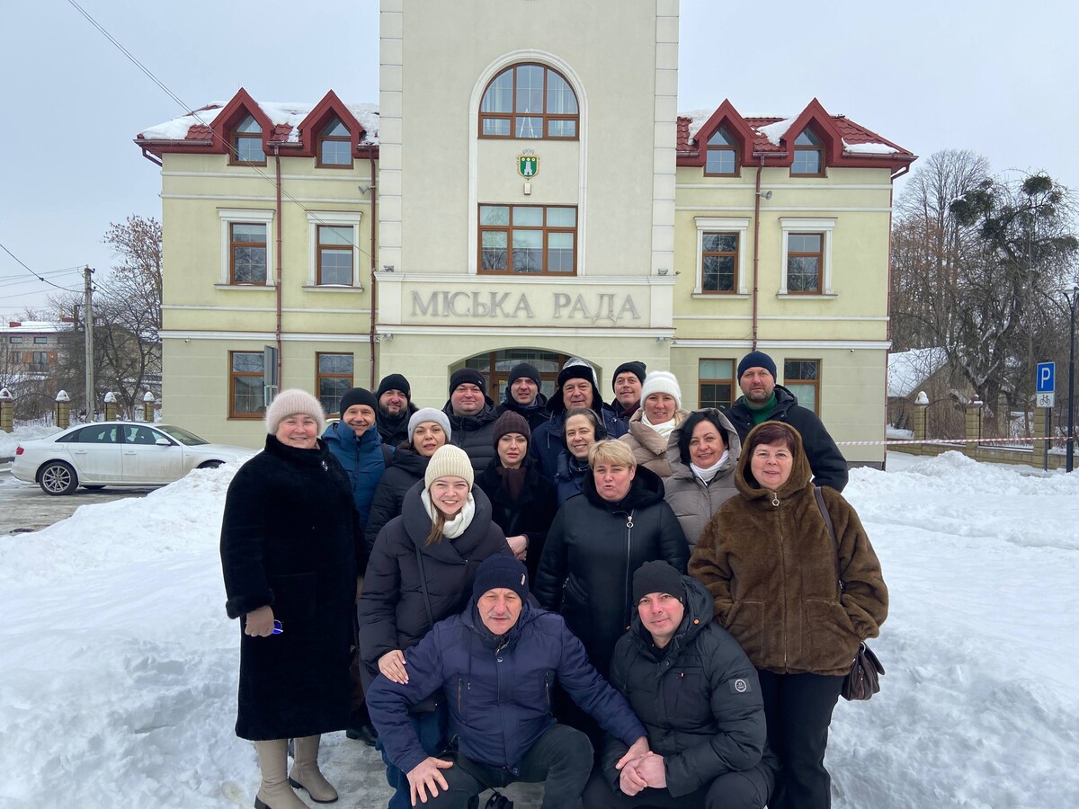 Учасники делегації у Пустомитах, на другому плані - будівля міської ради