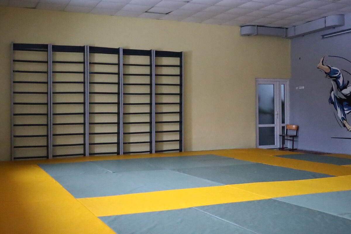 Спортивний простір з спеціальним м&rsquo;яким покриттям з матів у жовто-синіх кольорах, яке підходить для занять єдиноборствами, гімнастикою або іншими видами спорту. Уздовж стіни розташовані шведські стінки для фізичних вправ і розтяжки. Стіни пофарбовані у світлі тони, а на одній з них є яскравий спортивний настінний малюнок із зображенням спортсмена в русі.