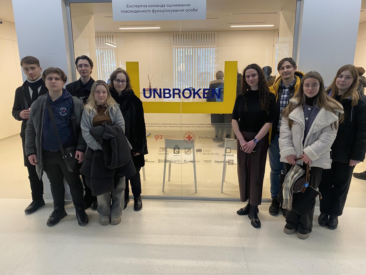 учасники фестивалю вертепів у центрі НЕЗЛАМНІ (UNBROKEN) під час екскурсії біля емблеми центру