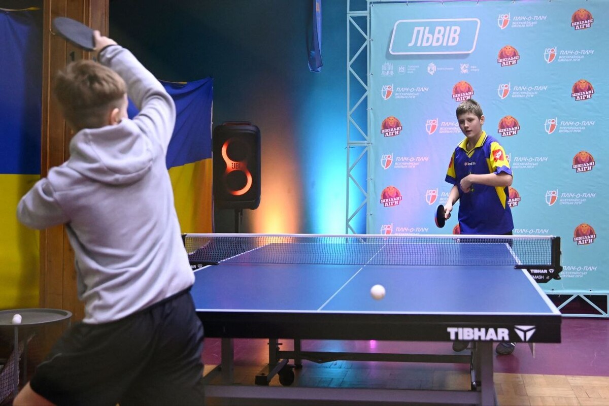 Хлопці у спортивній формі грають у настільний теніс.