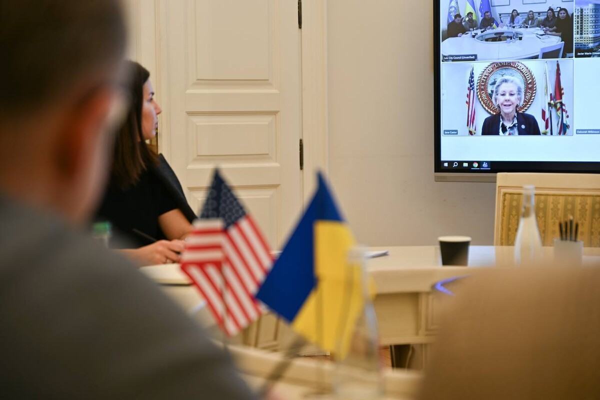 На великому екрані під час онлайн-зустрічі очільниця американського міста Тампа Джейн Кастор. На столі у Білій залі Львівської міськради два прапорці України та США.