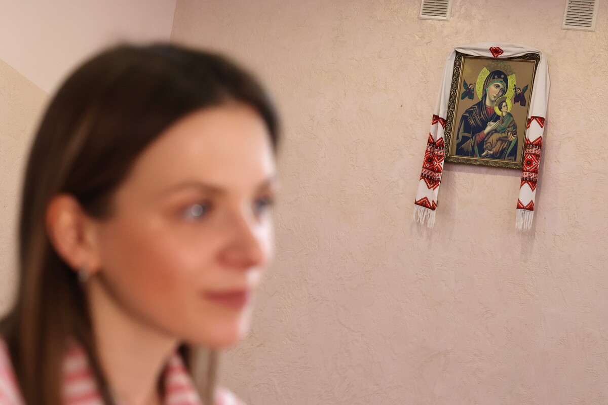 Трішки розмите портретне фото обличчя Устини на передньому плані, а на задньому тлі на стіні висить ікона Богородиці