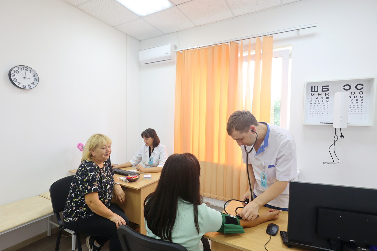 В кабінеті лікаря відбувається огляд пацієнтів. Одній із відвідувачок вимірюють артеріальний тиск