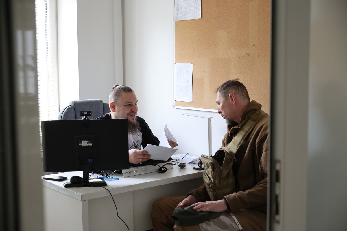 У Центрі допомоги бійцям: за столом сидять і спілкуються керівник центу Андрій Жолоб та ветеран
