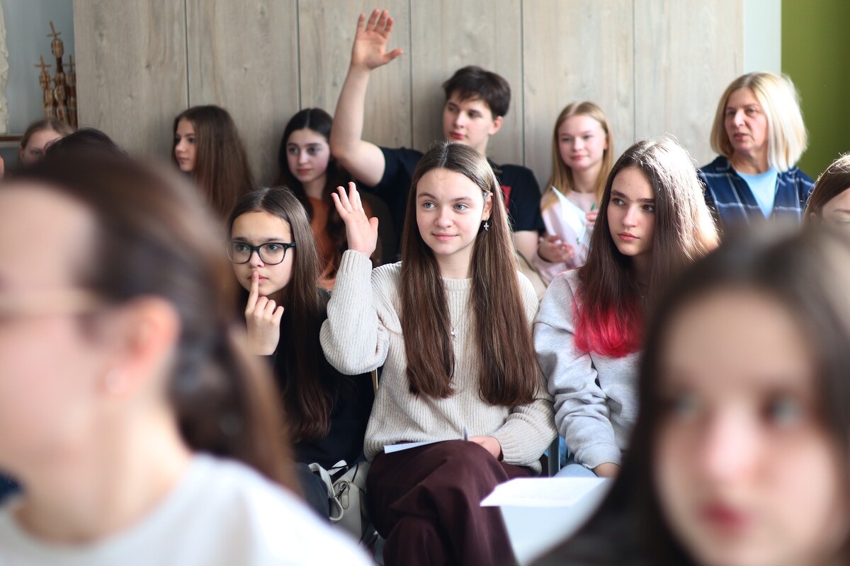 Учні сидять у шкільному класі та піднімають руки. Фото Юлії Олексин.