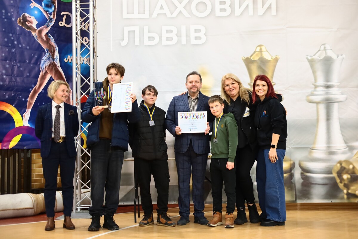 Група дорослих та дітей позує на фоні великого банера &laquo;Шаховий Львів&raquo;, тримаючи в руках дипломи та кубки.