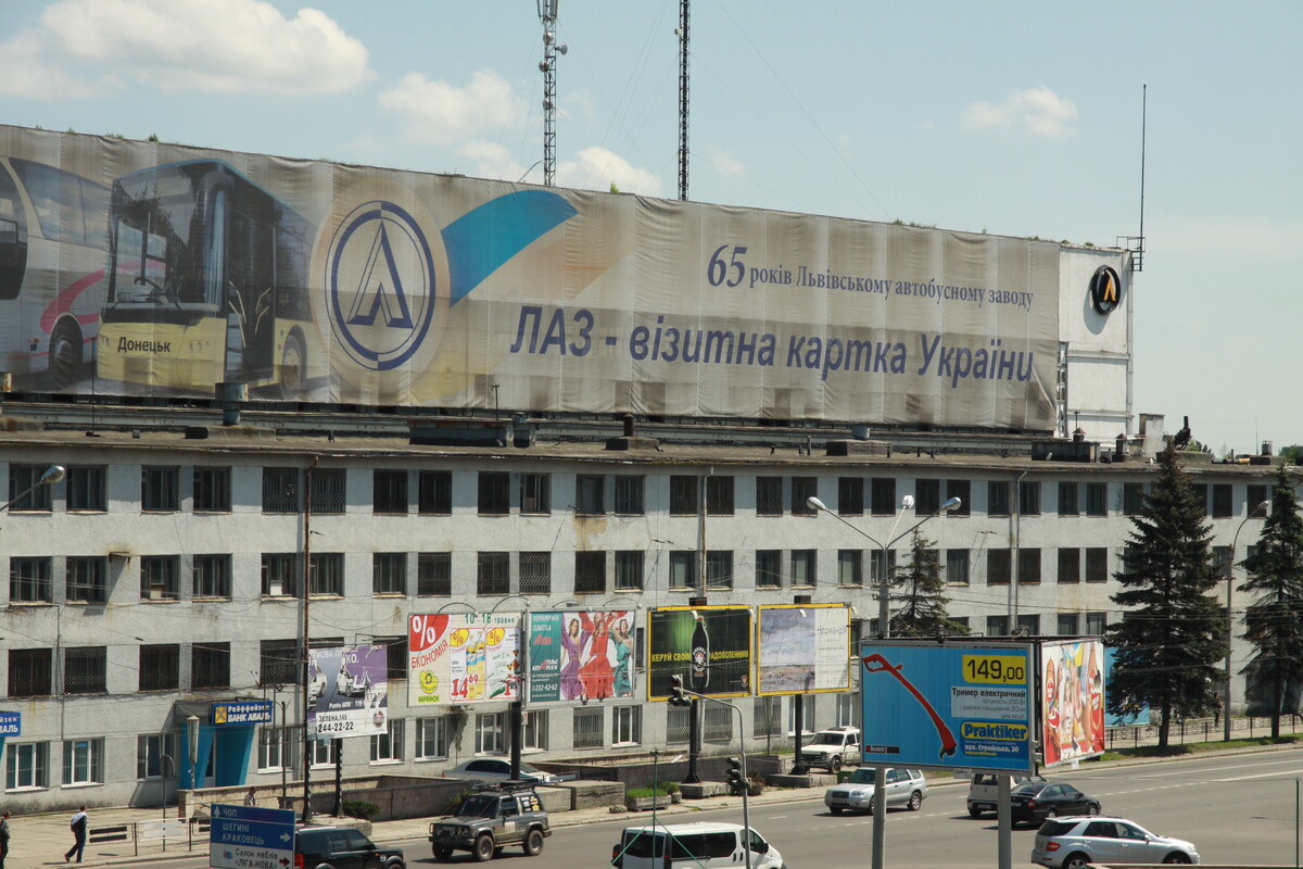 будівля колишнього ЛАЗу вздовж міської магістралі. На даху споруди розміщений великий банер із написом: &laquo;65 років Львівському автобусному заводу. ЛАЗ &ndash; візитна картка України&raquo;, а також зображенням автобуса і логотипом підприємства.