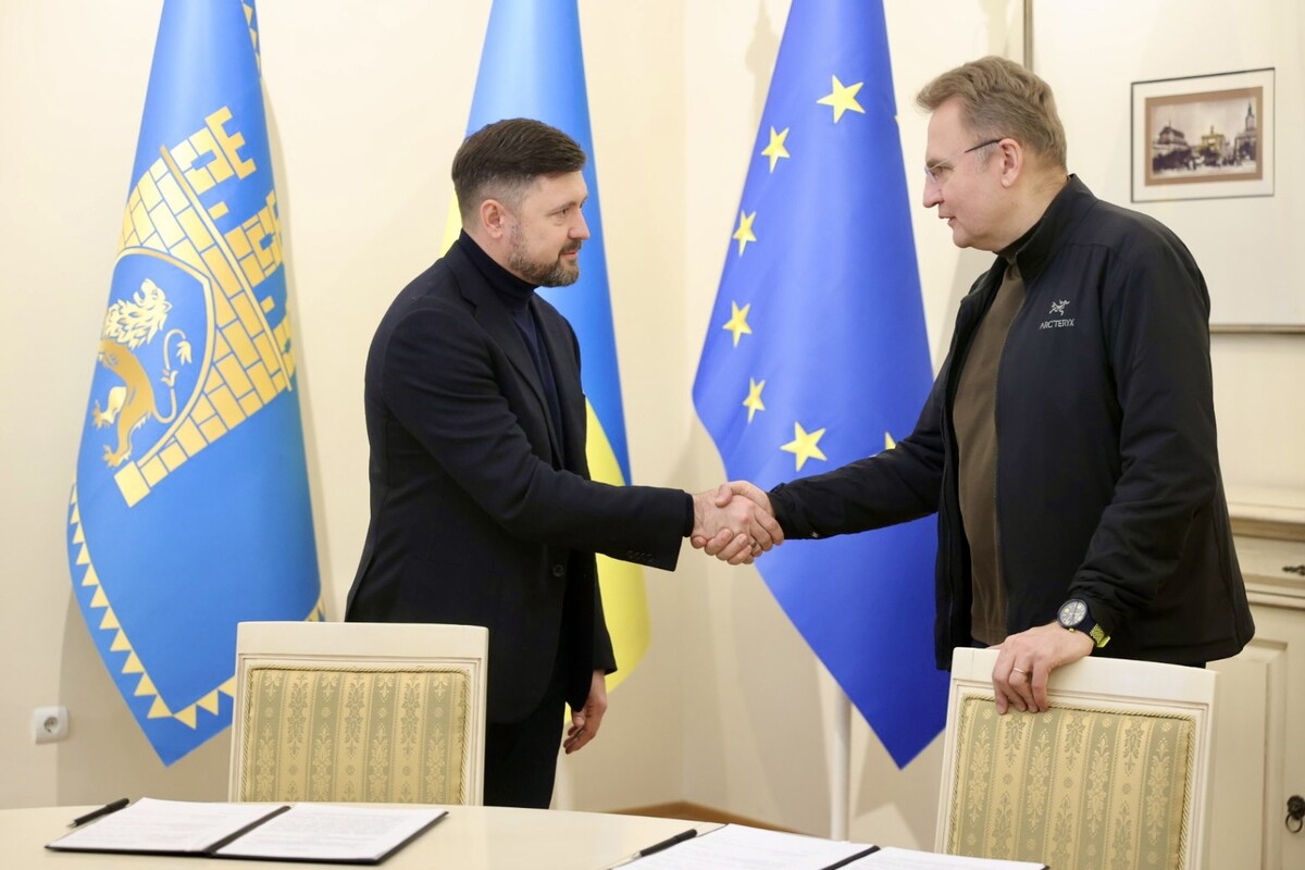 Мер Львова Андрій Садовий та мер Маріуполя Вадим Бойченко тиснуть руки одне одному на фоні прапорів ЄС, України та Львова в Білій залі Львівської міської ради