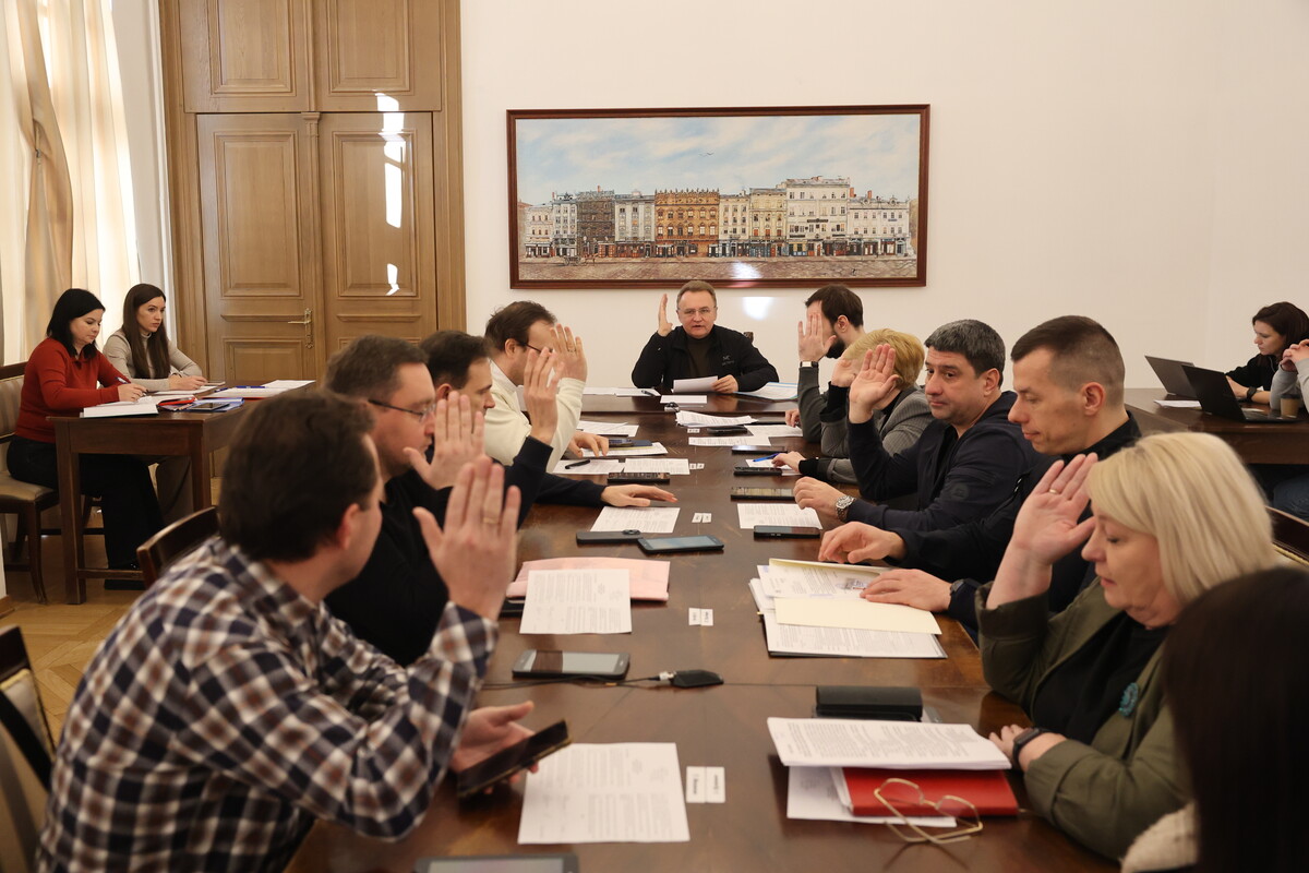 Момент, коли члени виконавчого комітету голосують: усі сидять за столом і одночасно підняли руку