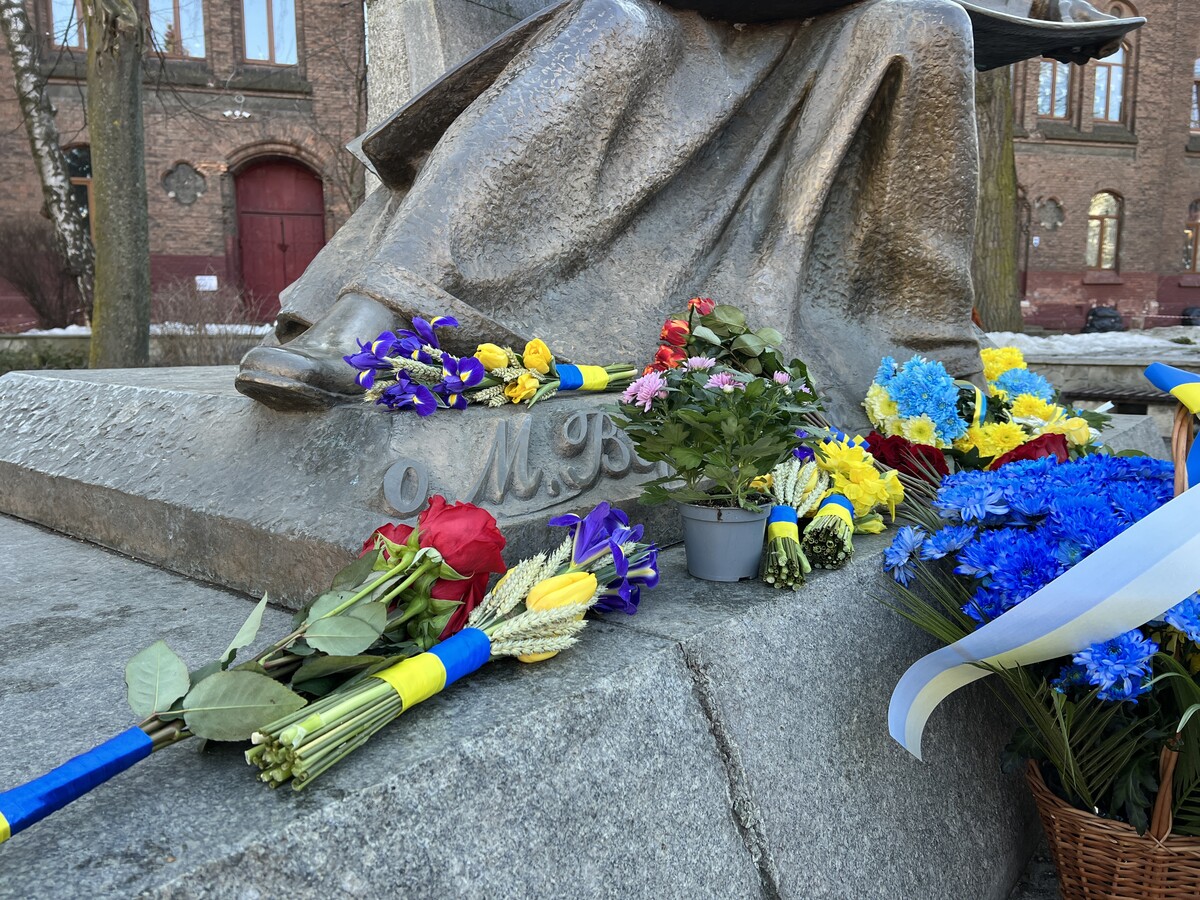 На підніжжі пам&rsquo;ятника Михайлу Вербицькому розкладені букети живих квітів, перев&rsquo;язані синьо-жовтими стрічками. Поруч стоїть кошик із жовто-блакитними хризантемами та горщик із квітами.