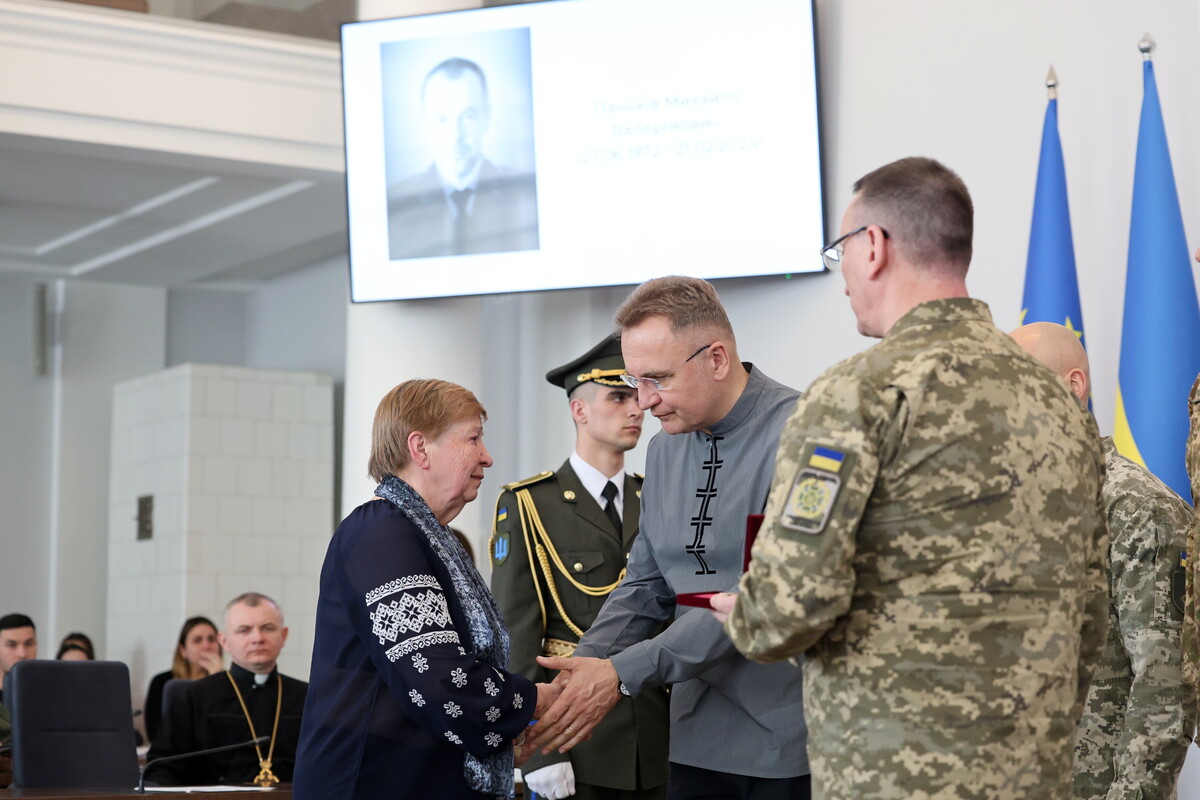 Міський голова Львова Андрій Садовий вручає &laquo;Почесний знак святого Юрія&raquo; жінці. Поруч стоять військовослужбовці.