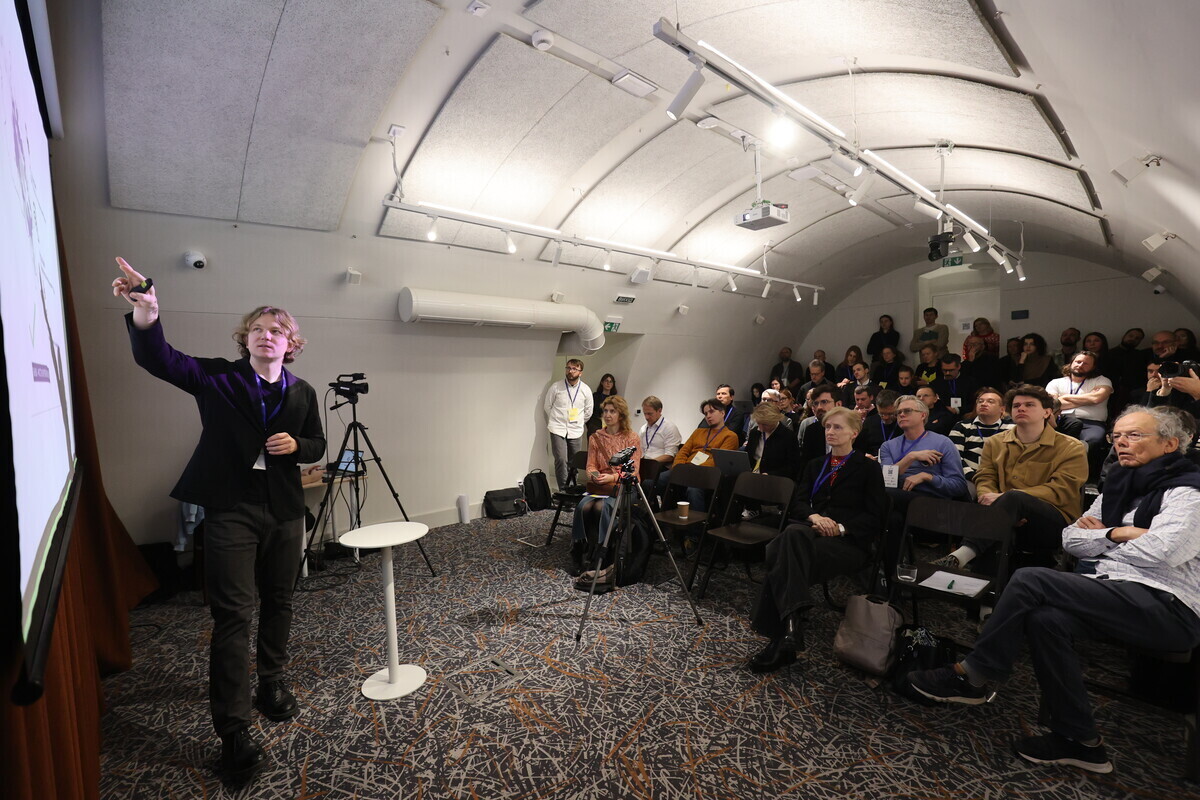 Головний архітектор Львова Антон Коломєйцев виступає та показує презентацію на великому екрані в Музеї міста перед кількома десятками людей, учасниками команд, що займаються тестовим плануванням північного Львова