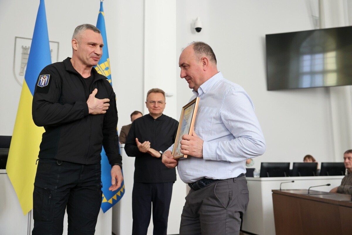 Мер Києва вручає подяку одному із працівників львівських комунальних підприємств, який допомагав столиці подолати наслідки ворожих обстрілів. Поруч з ними - мер Львова.