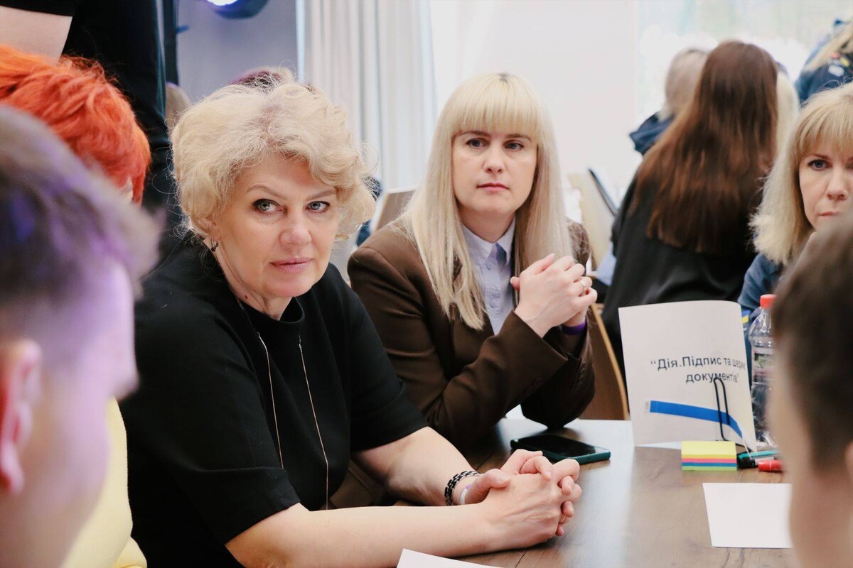 Група з учасників форуму сидить навколо столу та спільно обговорюють ідеї розвитку адміністративних послуг в Україні