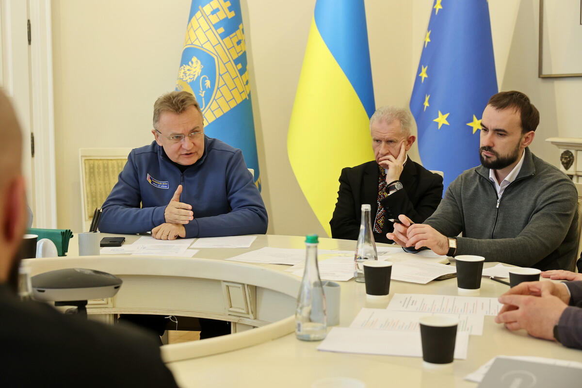 Міський голова Львова Андрій Садовий, віцепрезидент Українського католицького університету отець-доктор Богдан Прах та керуючий справами виконавчого комітету Львівської міської ради Євген Бойко сидять за круглим столом у білій залі Ратуші.