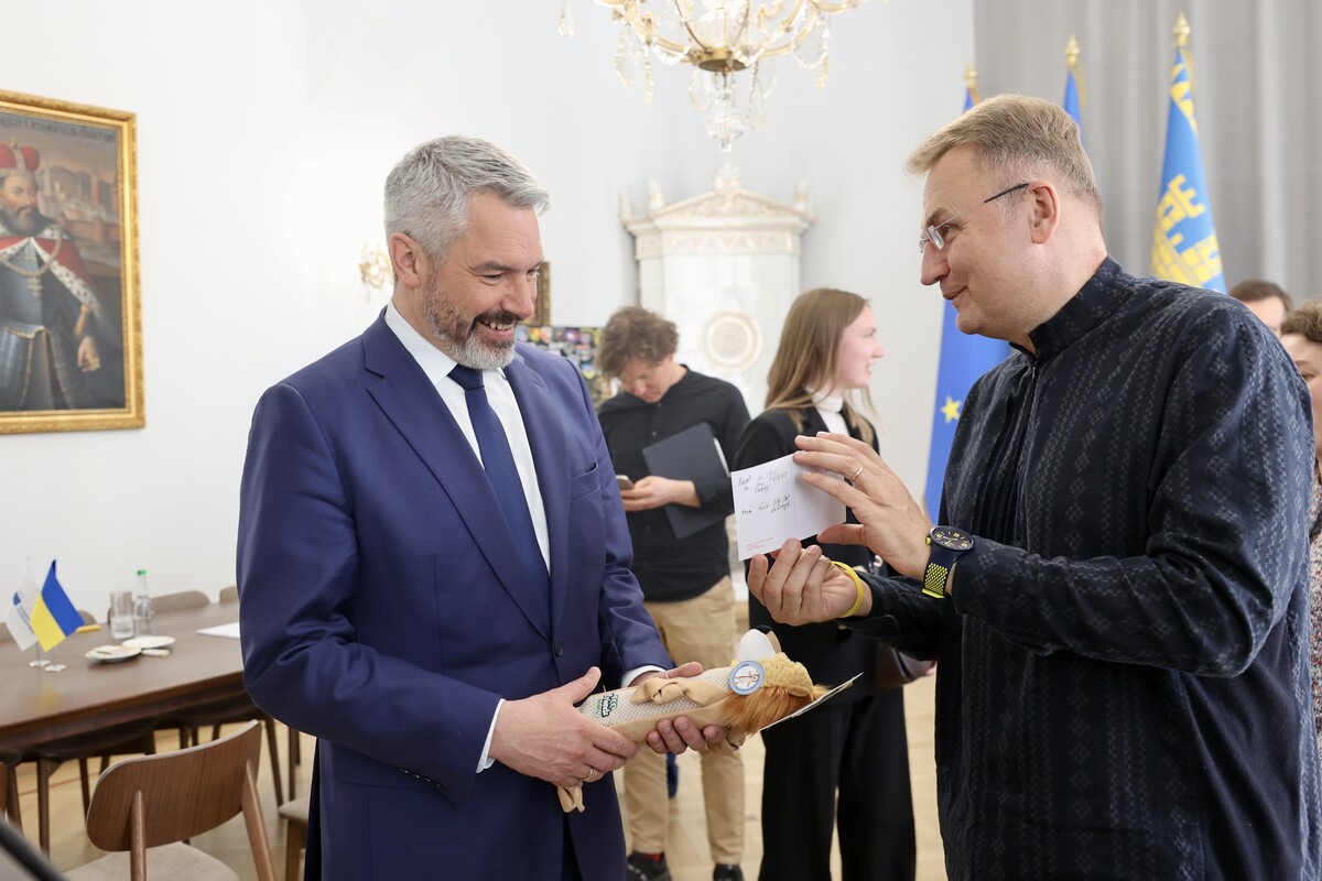 Міський голова Андрій Садовий дарує іграшку для улюбленця Карла Негаммера від імені котячого мера Левчика. Обоє чоловіків усміхаються