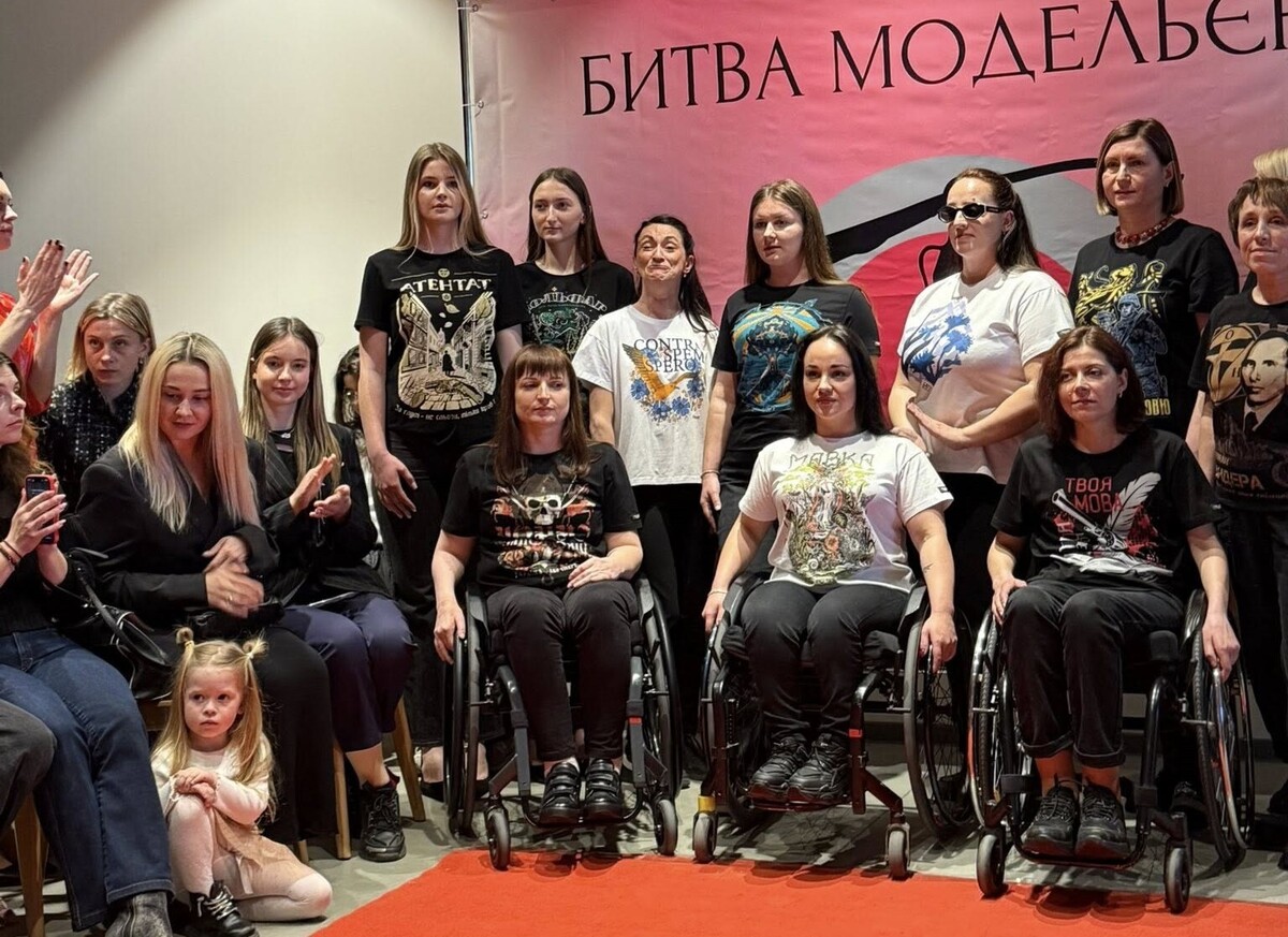 На фото моделі Інклюзивної модельної школи «НовіМИ». Частина учасниць на кріслах колісних. Вони всі усміхаються та позують для спільного фото