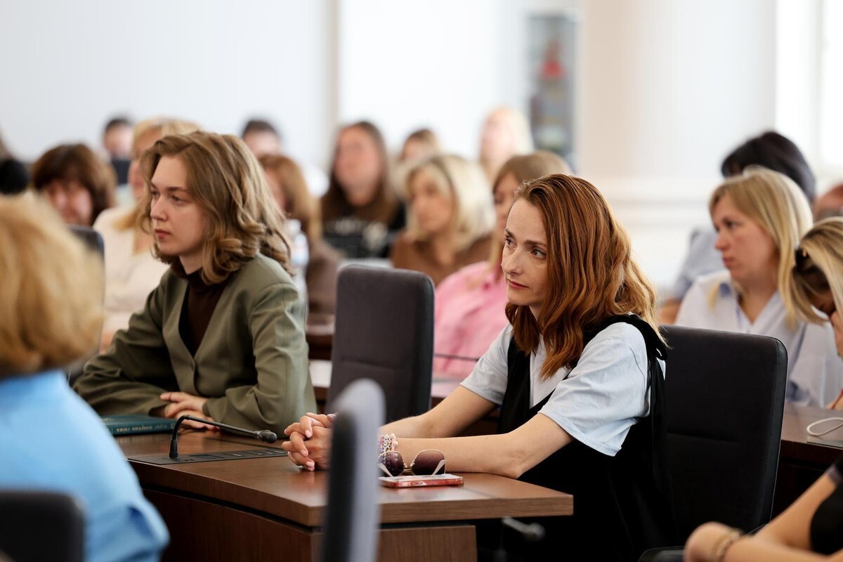 Учасники події уважно дивляться в сторону спікерів. Позаду видно, що зал заповнений людьми