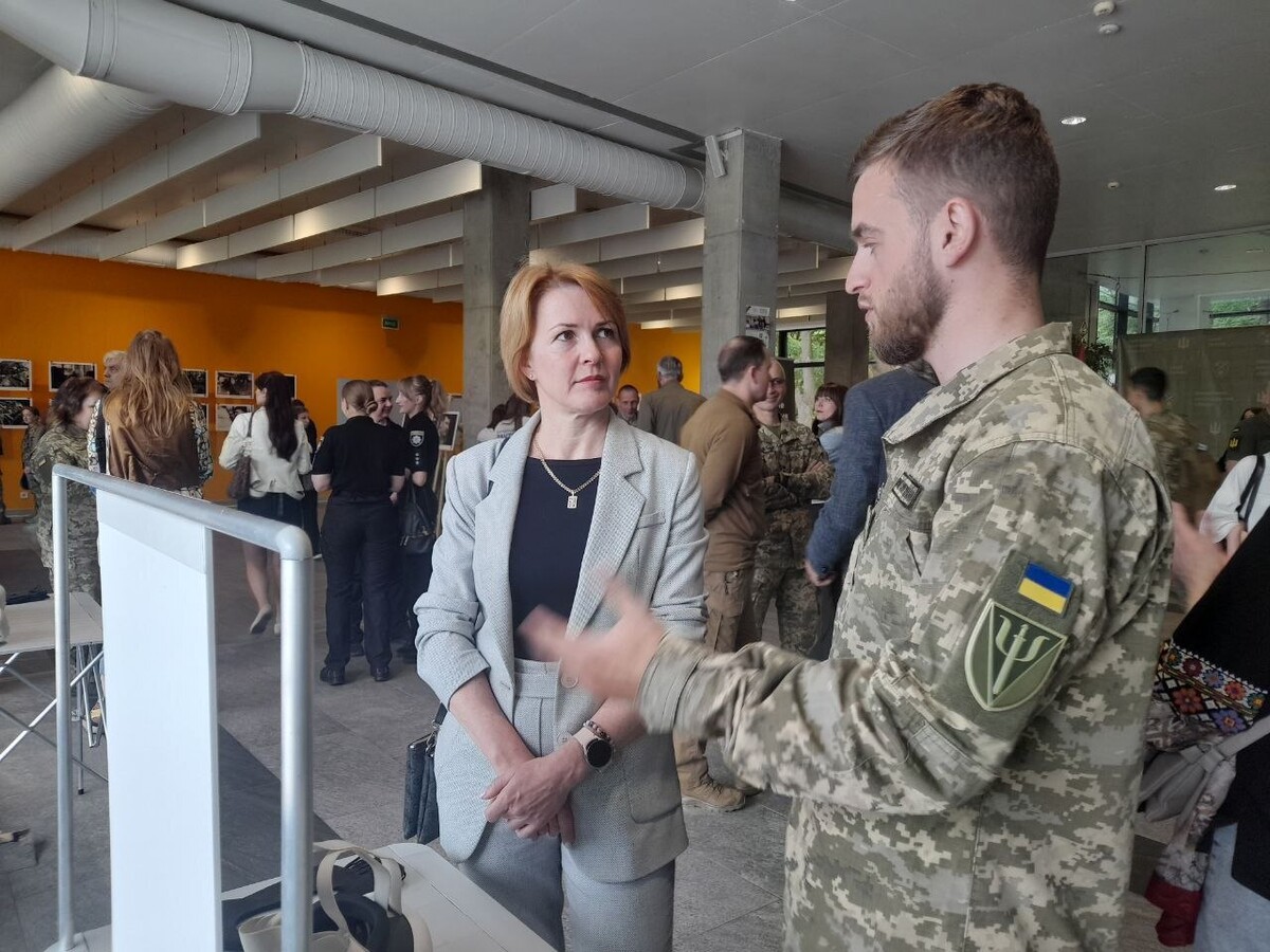 Керівниця департаменту гуманітарної політики Львівської міської ради Валентина Бартошик та чоловіка у військовій формі стоять у приміщенні, дивляться один на одного та розмовляють.