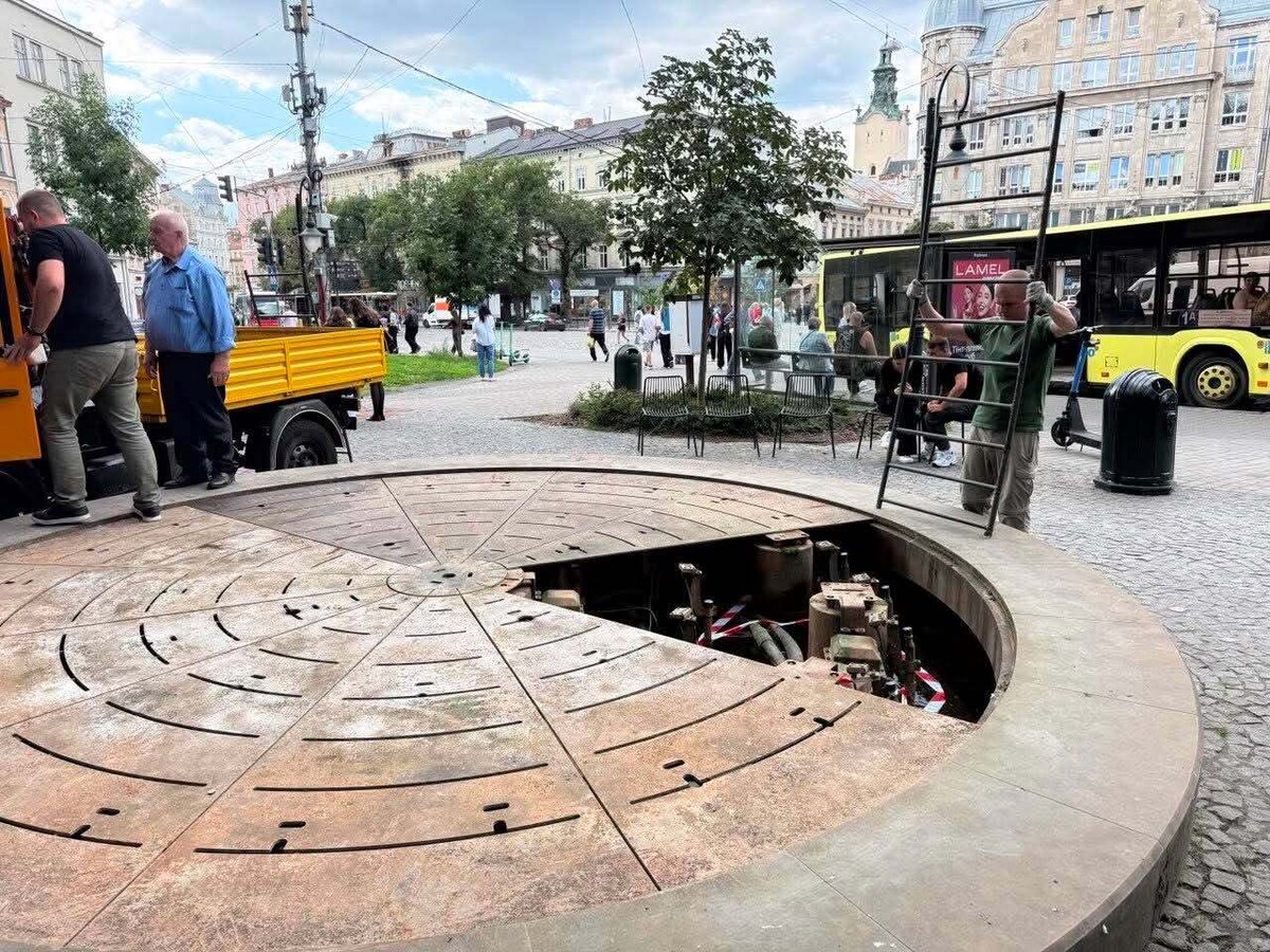 Працівники демонтовують металеві плити з фонтану.