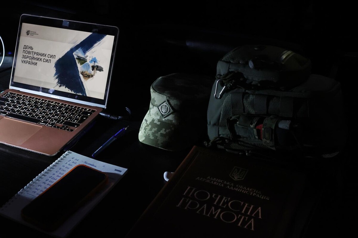 Робоче місце, підготовлене до урочистого заходу ЗСУ. На екрані ноутбука відображена тематична презентація, поруч лежать блокнот із записами, ручка та мобільний телефон. Праворуч видно військовий кашкет, тактична сумка та почесна грамота.