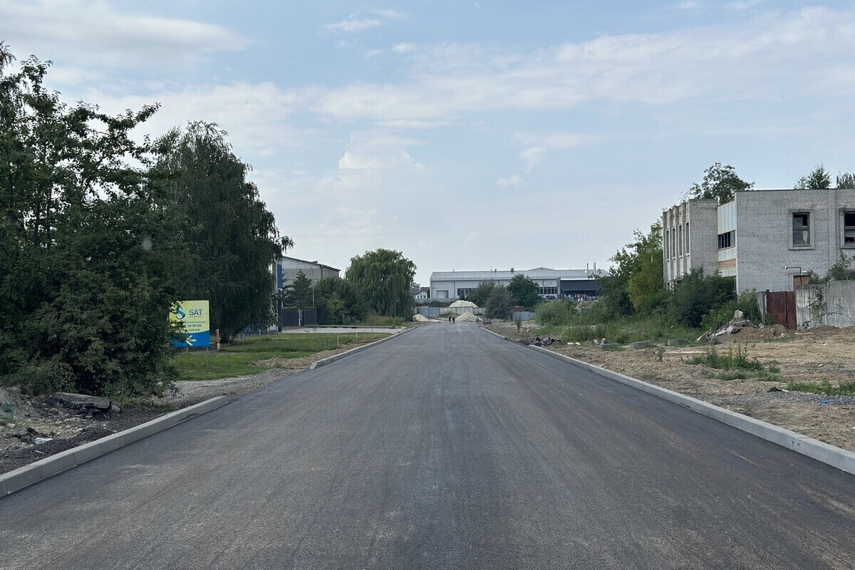 Відремонтована ділянка вул. Конюшинної після влаштування нового асфальтного покриття. Рівна широка дорога простягається вперед, а з обох боків облаштовано нові бордюри.
