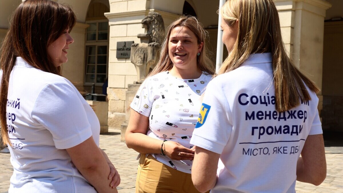 Працівниці у футболках з написами &laquo;Соціальний менеджер громади&raquo; біля міської ради спілкуються між собою