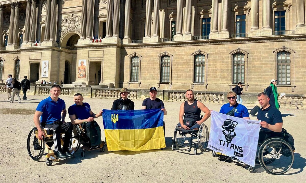 Львівські ветерани на одній із площ Парижу тримають прапори України та клубу &laquo;Титани-Львів&raquo;