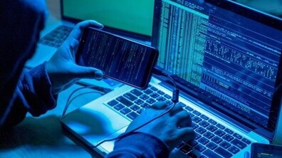 Ілюстративне фото. Чоловік тримає в руці телефон, приєднаний до ноутбука. Намагається завантажити дані з одного девайсу на інший