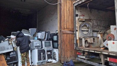 Працівник комунального підприємства оглядає великогабаритне сміття. Поруч видно частину вантажного авто.