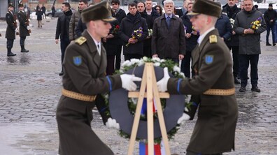 Президент Чехії Петр Павел у супроводі офіційної делегації під час церемонії вшанування пам’яті полеглих захисників на Личаківському цвинтарі. На передньому плані двоє українських військових почесної варти встановлюють пам'ятний вінок на дерев’яну підставку. Петр Павел стоїть у центрі групи людей. Поруч — міський голова Андрій Садовий та інші посадовці з квітами в руках.