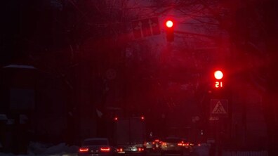 На темній вулиці з автомобілями горить червоний сигнал світлофора з таймером