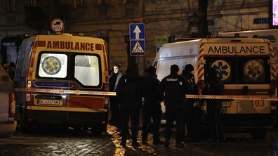 Дві карети швидкої допомоги та група поліцейських біля них стоять на вулиці вночі. Місце огороджене стрічкою, медики й правоохоронці працюють на місці події.