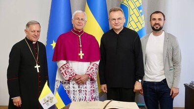 Архієпископ Ренато Боккардо, міський голова Львова Андрій Садовий та керуючий справами виконкому Євген Бойко стоять біля столу, на якому розташована Книга почесних гостей міста.