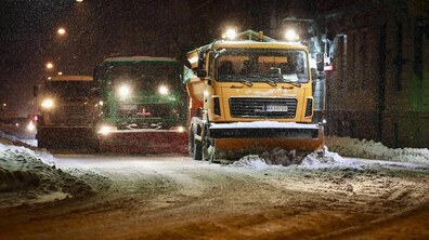 Снігоприбиральна техніка чистить дорогу у темну пору доби.
